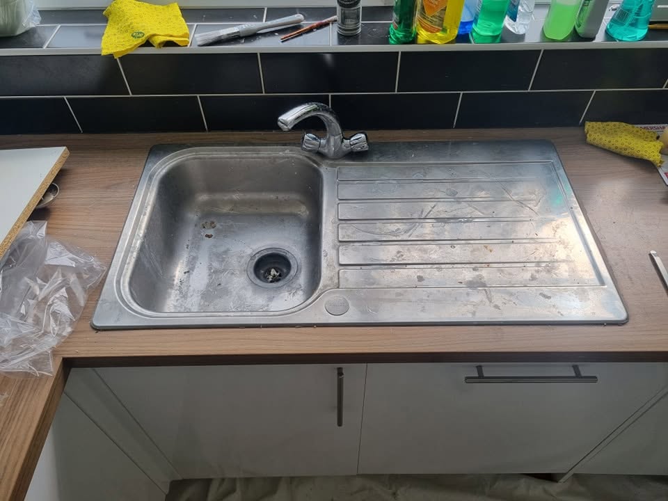 Old worn stainless steel kitchen sink before replacement