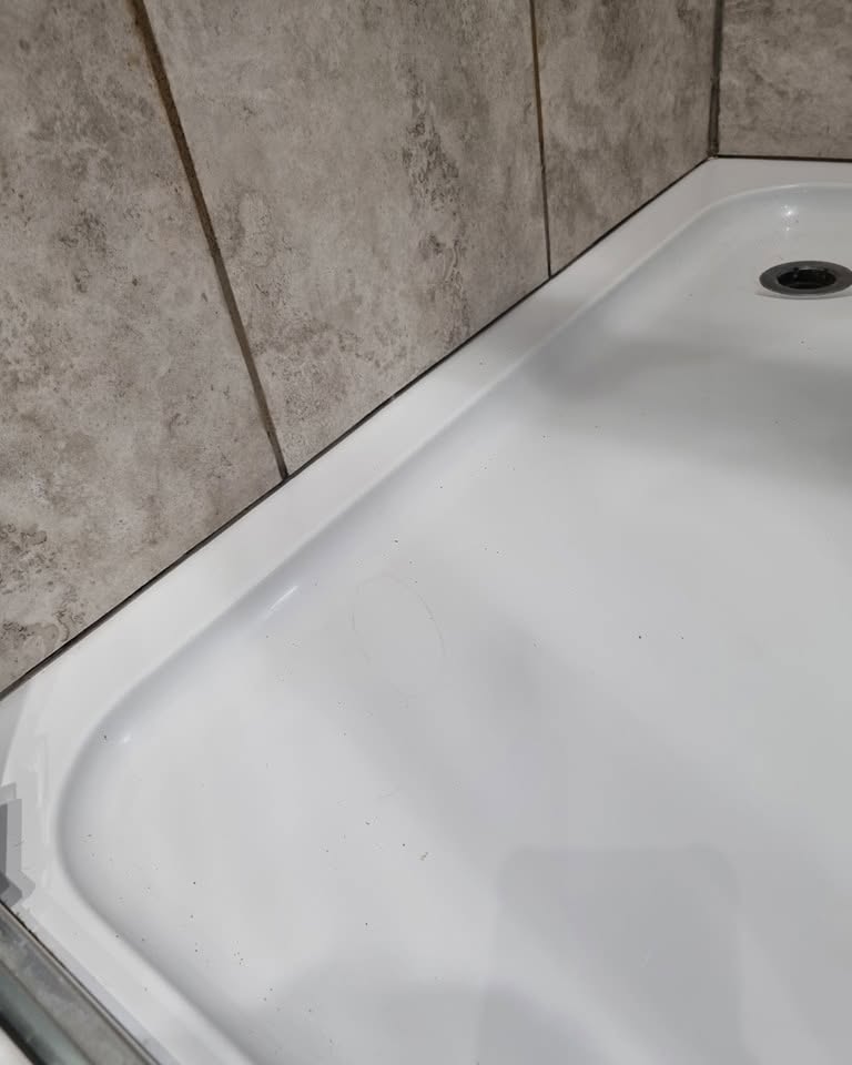 Cleaned shower tray with fresh sealant after work
