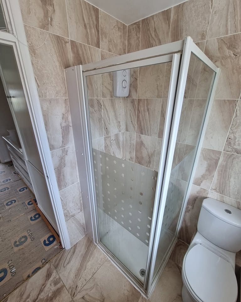 Shower cubicle installation in progress in a marble-tiled bathroom