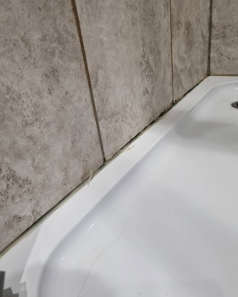 Dirty shower tray with mouldy sealant before cleaning